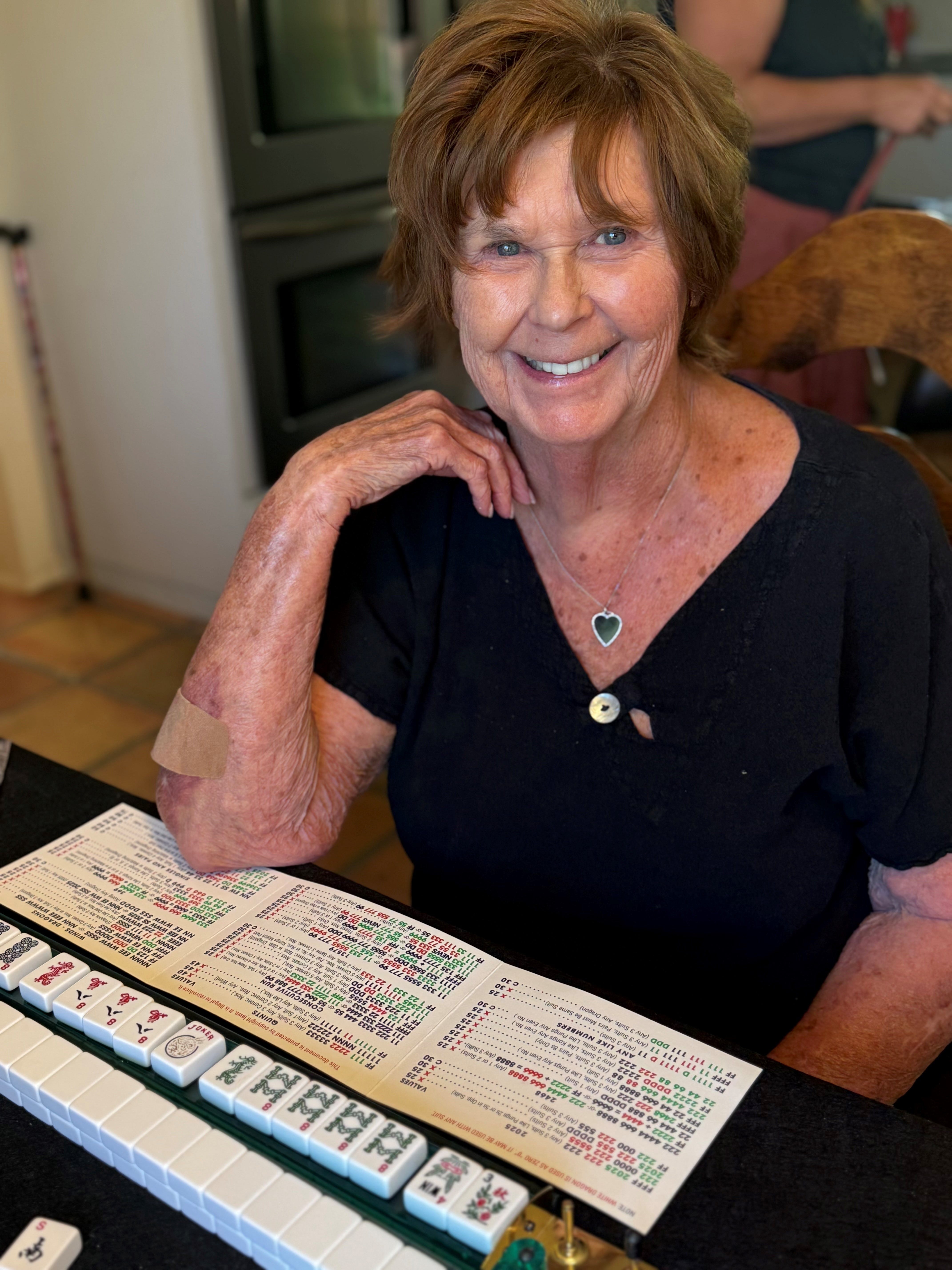 Nancy Guthrie, mother of "Today" show anchor Savannah Guthrie, smiles while sitting at a table with a Mahjongg card and tiles.