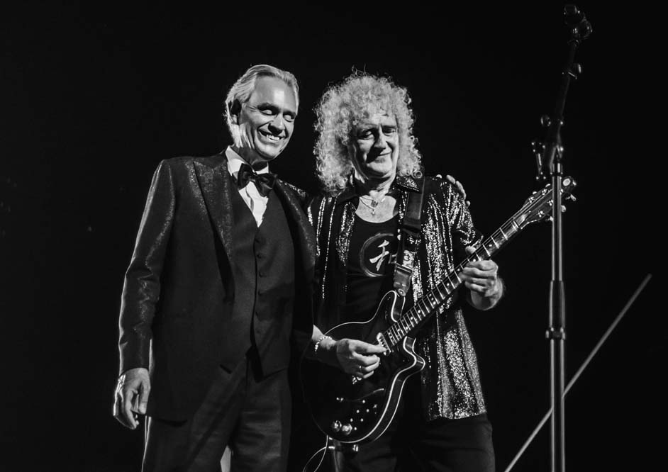 Black-and-white concert photograph of Andrea Bocelli beside Brian May holding his electric guitar at Teatro del Silenzio in 2024.