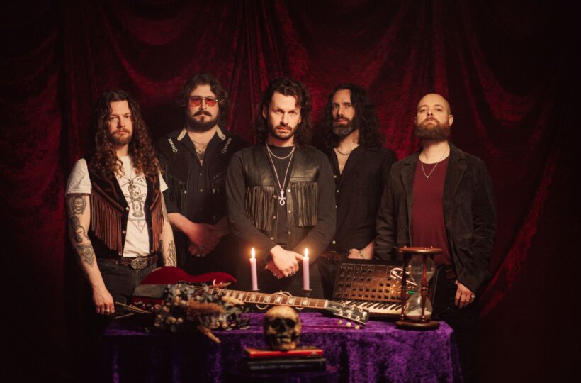 Green Lung's five members standing behind a table with instruments, candles and a skull