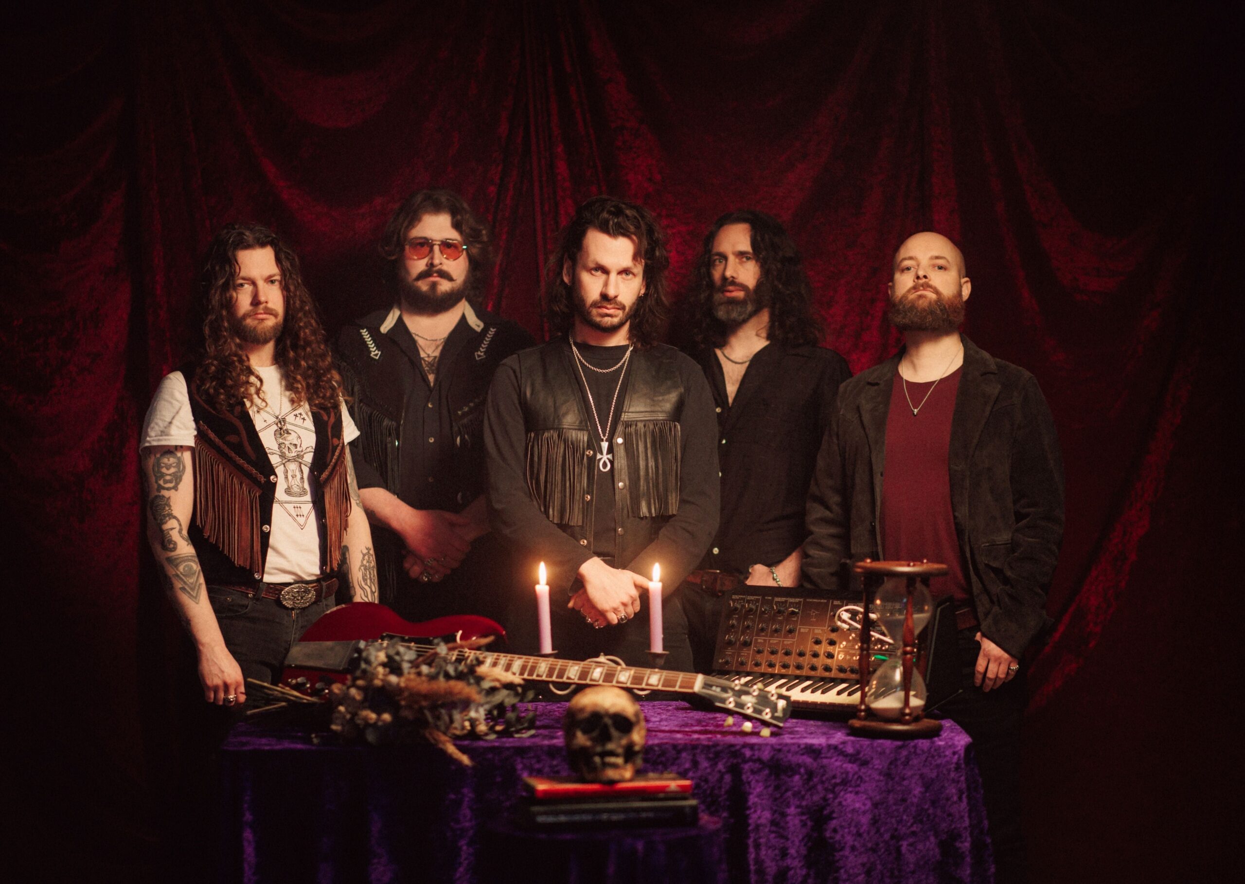 Green Lung's five members standing behind a table with instruments, candles and a skull