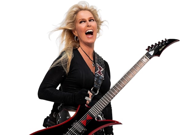 Lita Ford holding a black-and-red electric guitar against a white background