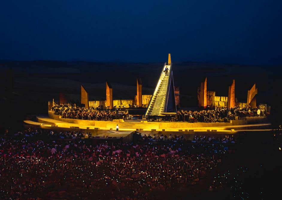 Wide view of the illuminated Teatro del Silenzio stage and audience during Andrea Bocelli’s 2024 anniversary concerts in Lajatico.